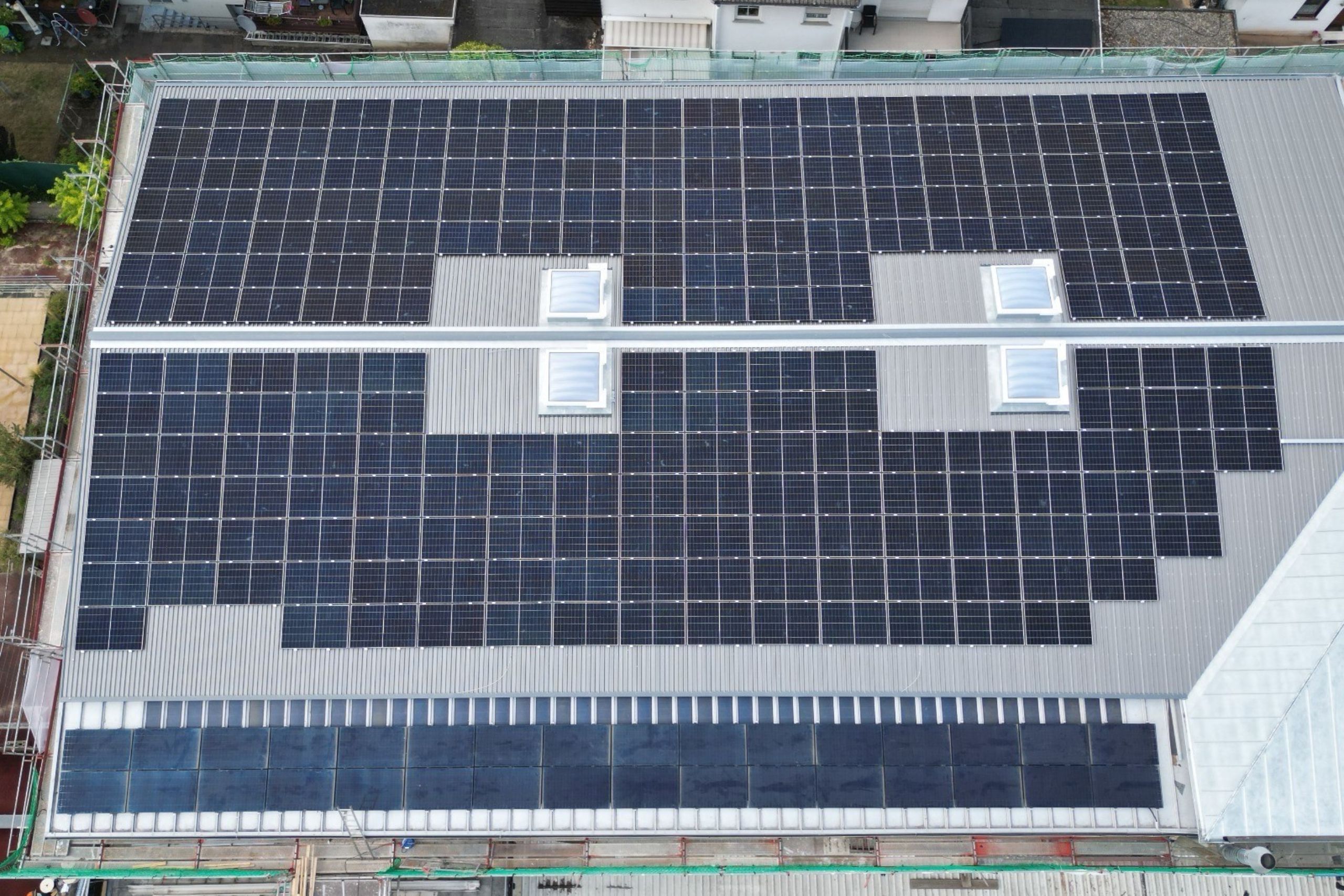 PV Anlage Aschaffenburg Gewerbeimmobilie Schweinheim Luftaufnahme einer gepflegten Gewerbeimmobilie, dessen Dach fast vollständig mit einer effizienten Photovoltaikanlage belegt ist. Der Blick fängt das gesamte Dach ein – ein Vorzeigeprojekt für Solaranlagen Aschaffenburg.